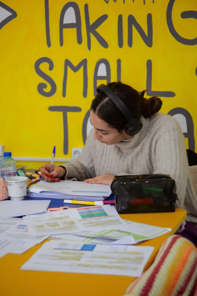 Étudiante concentrée dans l'espace de travail d'INCUB SPACE, devant un mur jaune